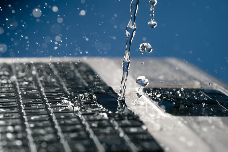 Closeup of stream of water splashing onto laptop keyboard