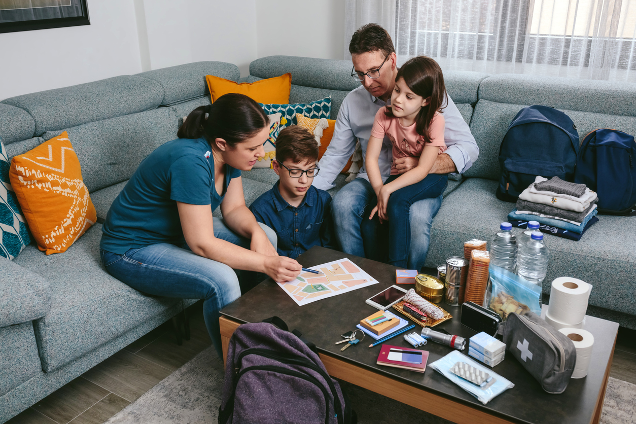 A Mother Explains The Escape Route Map While A Family Prepares Emergency Backpacks