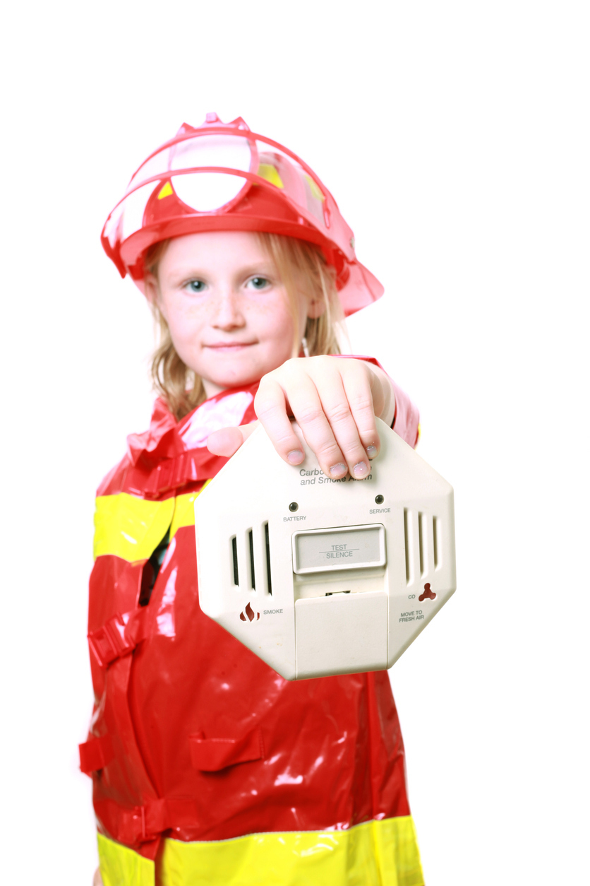 Girl With Firefighter Costume Holding Up Smoke Detector