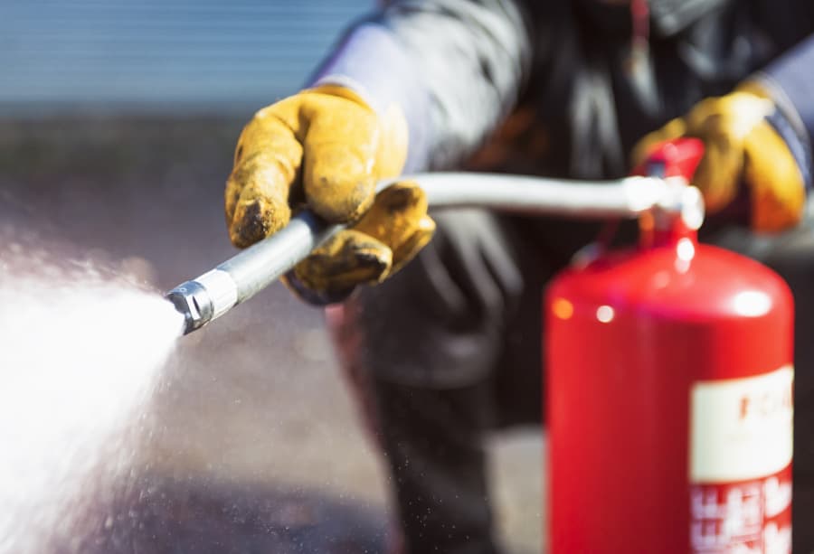 Fire extinguisher used by worker spraying extinguishing agent
