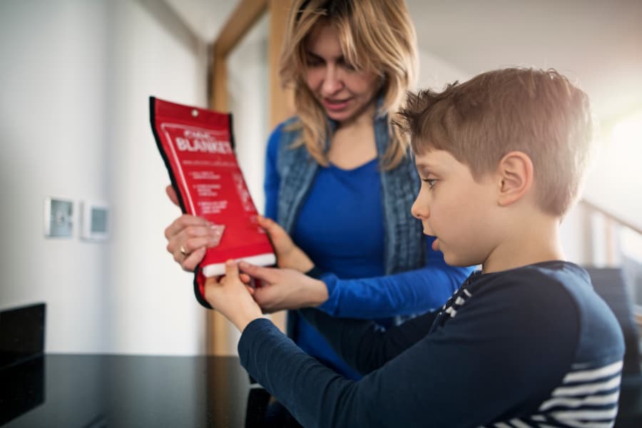 Mother explaining the use of a fire blanket to her son