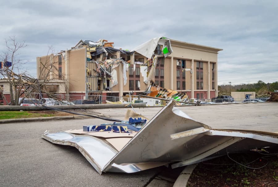 Aftermath of tornado shows roof torn off commercial property and parts deposited in street