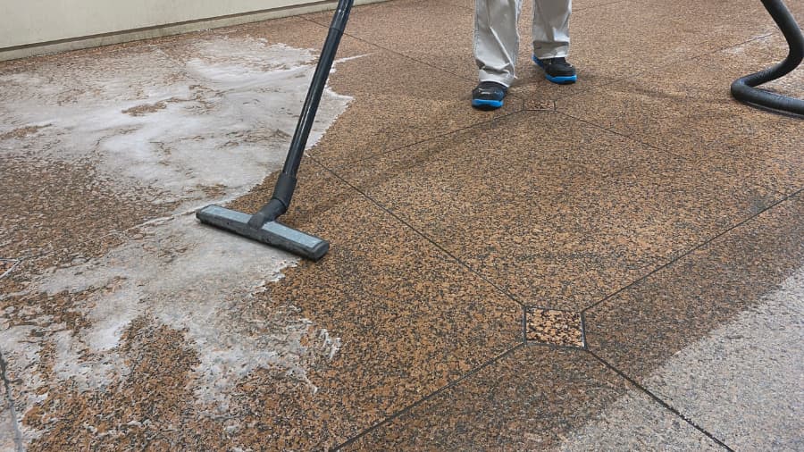 Technician uses professional vacuum to remove water from granite floor