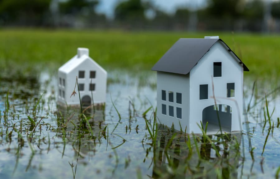 Toy homes submerged in puddle with grass