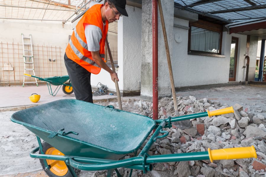 Worker in reflective vest moves rubble away as part of commercial fire damage restoration